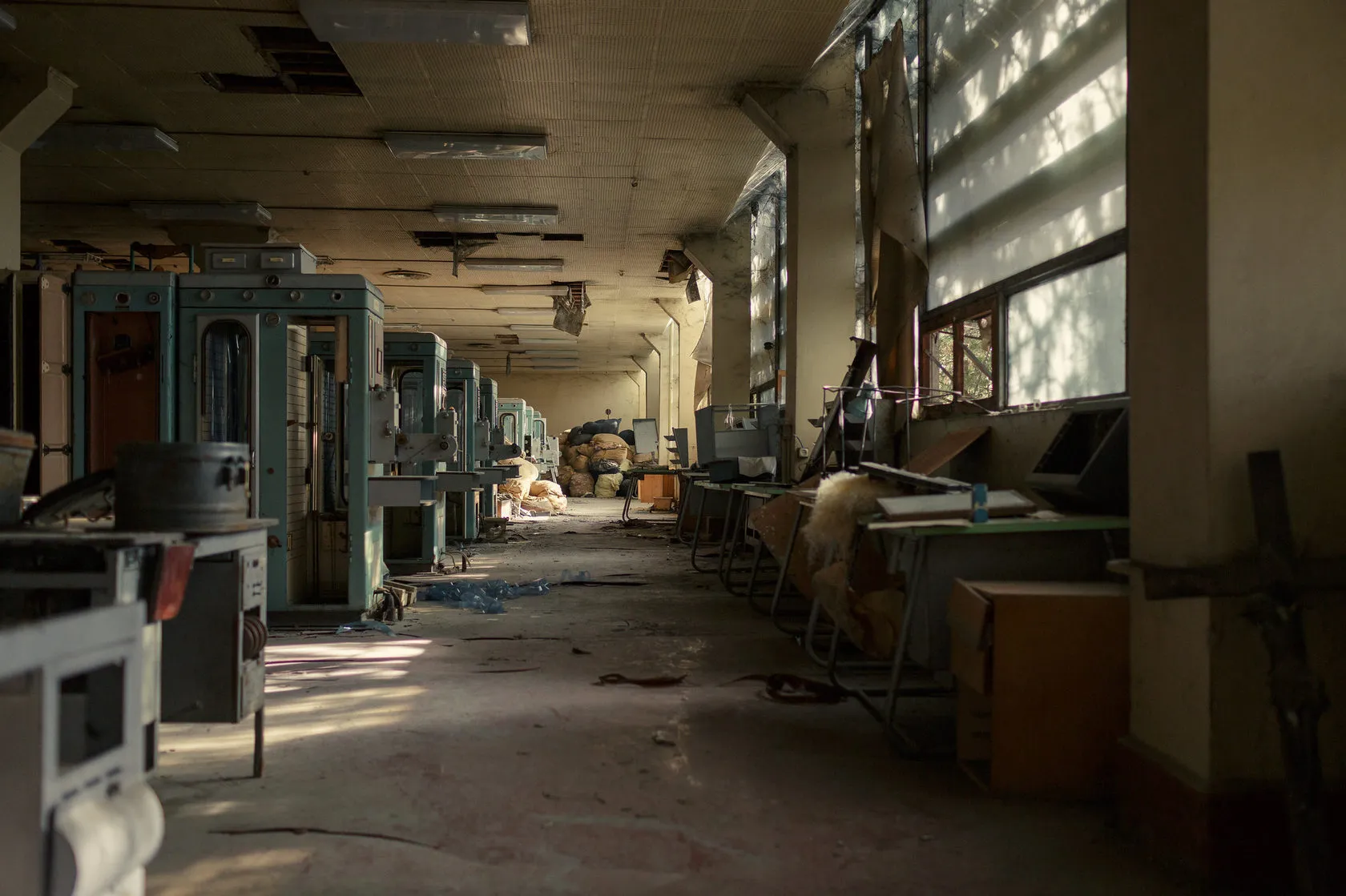 Kartuli Filmi by Andrei Kovalev: sunlight streams through an abandoned film studio's long, machine-lined corridor.