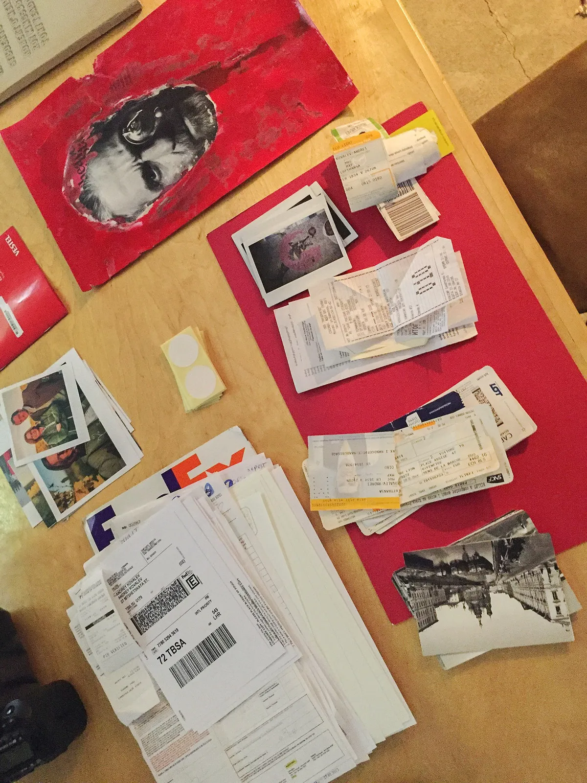 Old letters, photos and parcels piled on a red folder, seen from above.