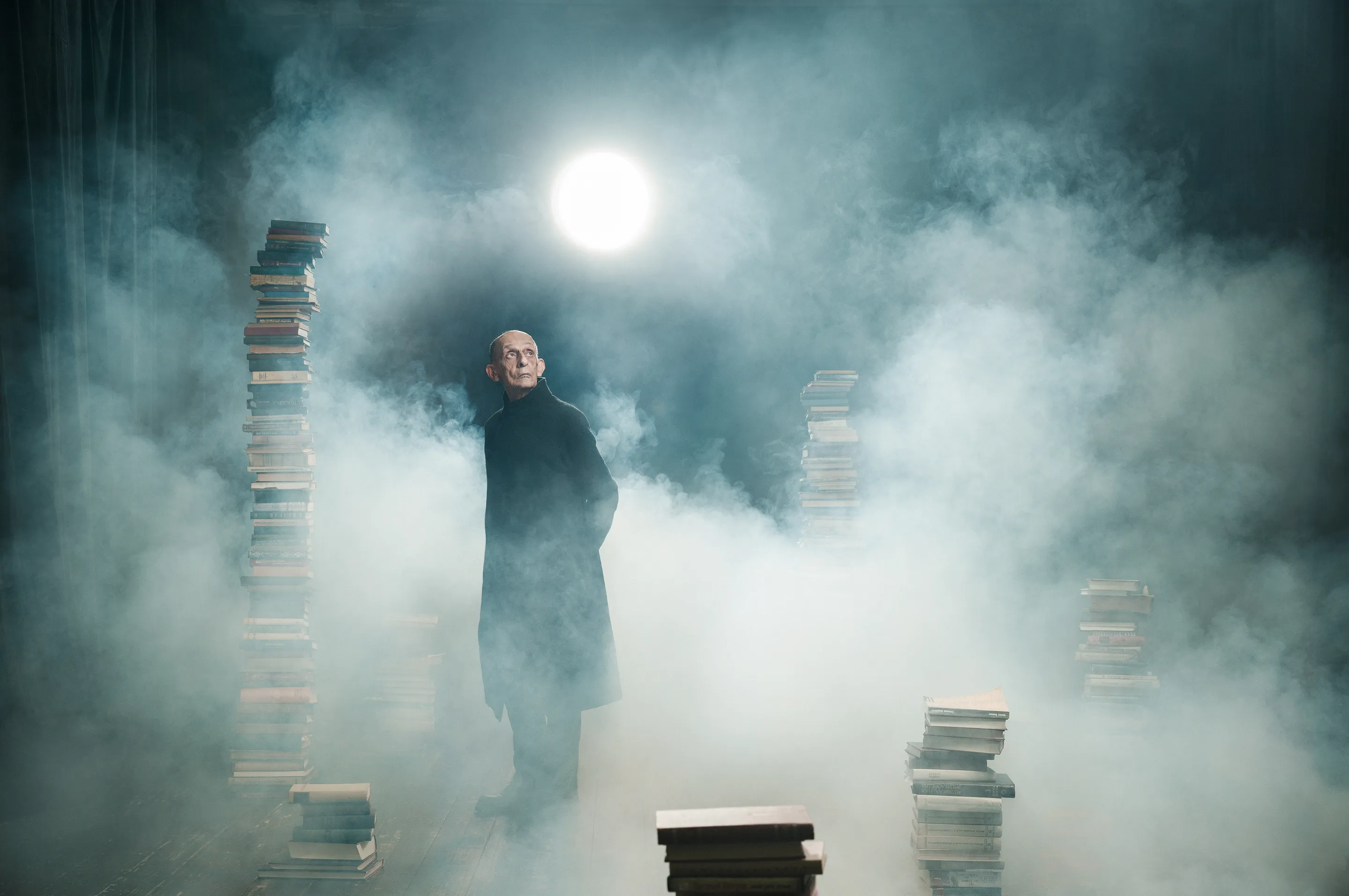 Literature portfolio by Andrei Kovalev: a man stands in smoke and light between towers of stacked books.