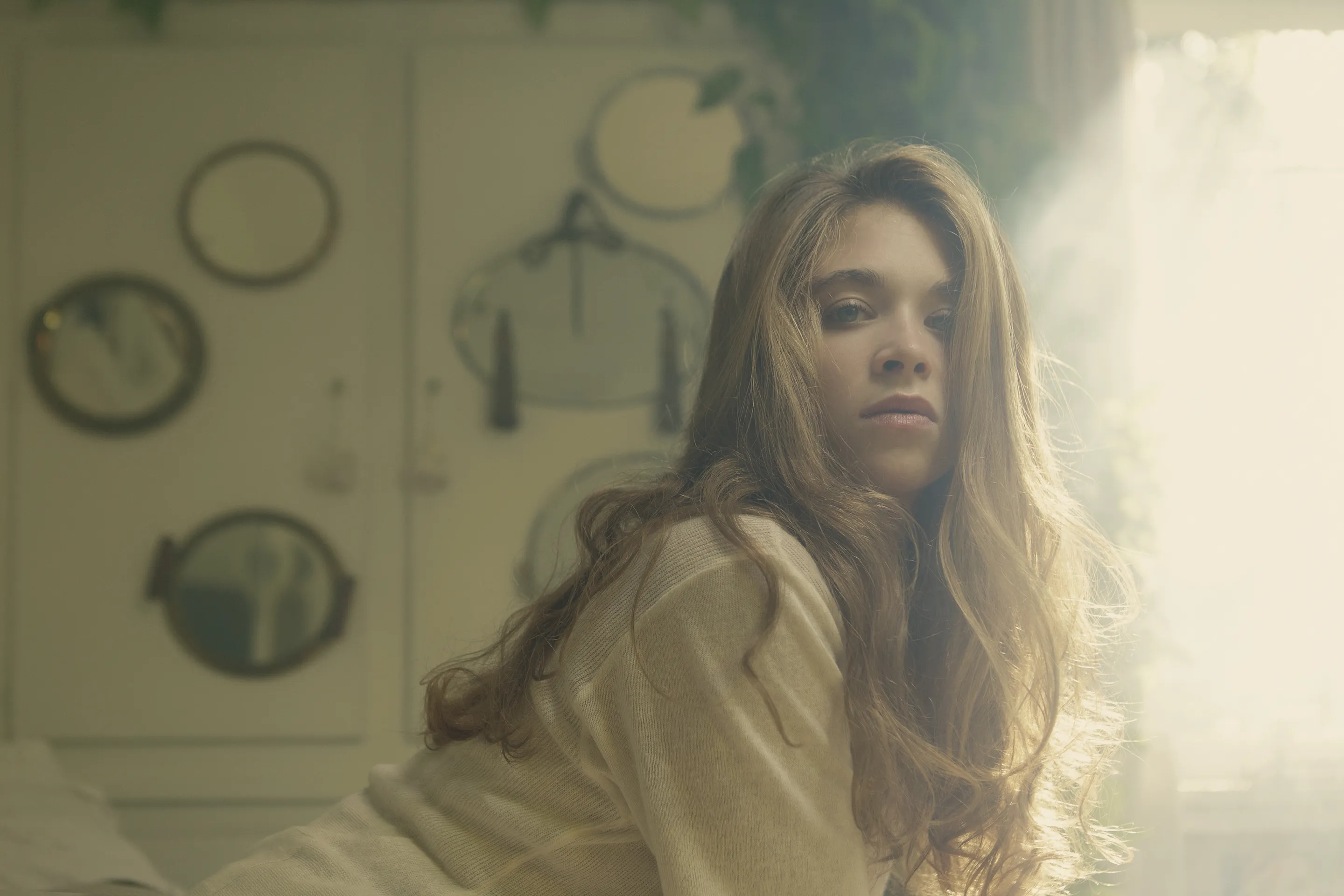 Emma Becker press portfolio by Andrei Kovalev: a woman glances back over her shoulder by a sunlit window.
