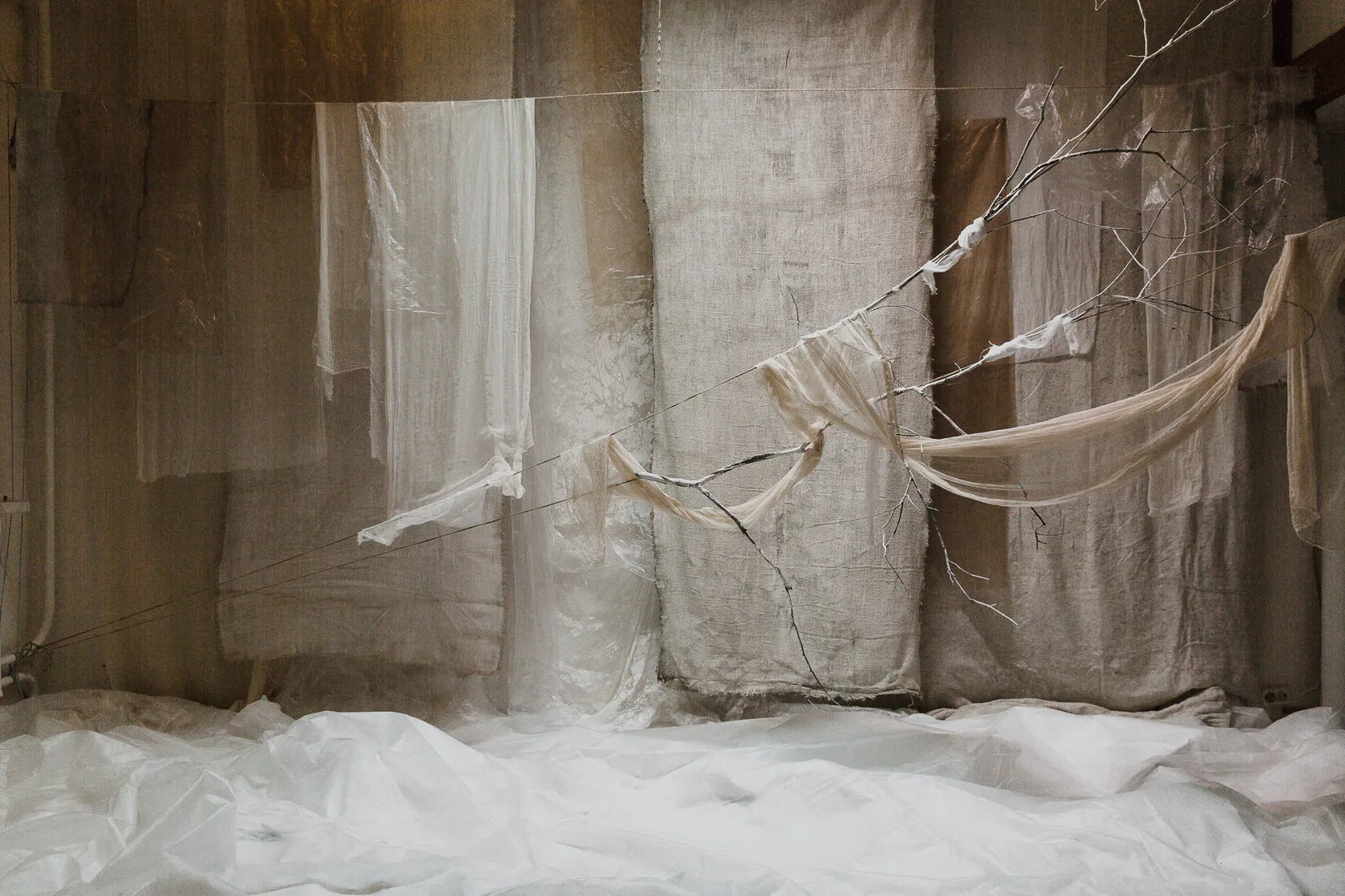 White Album key visual by Andrei Kovalev: draped white fabric and a bare branch form a quiet still life.