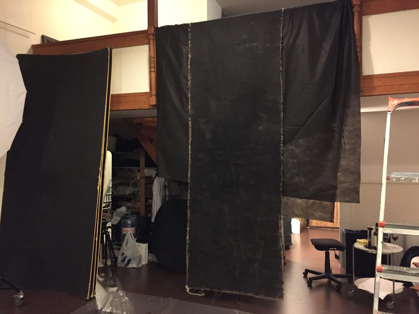 Black cloth panels hang from a rail as a backdrop in a studio.