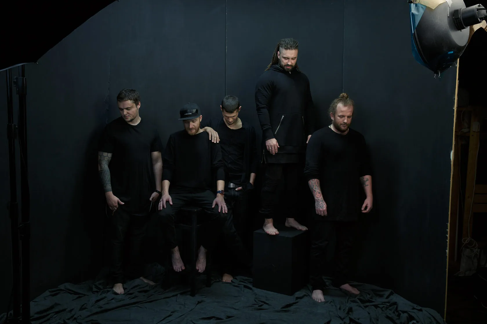 The five members of Burito, barefoot and in black, on a dark set lit by one lamp.