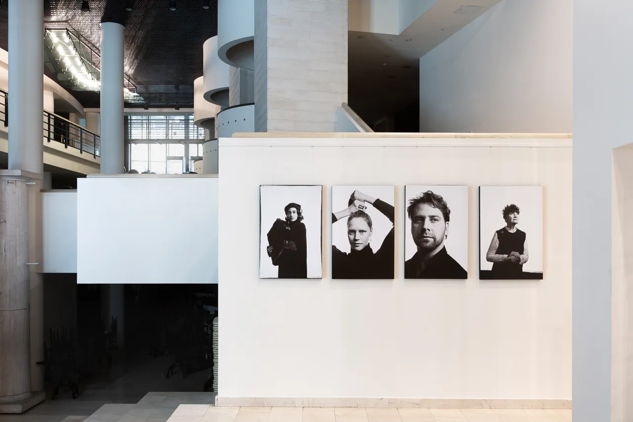 Four large cast portraits hang on a white wall in the theatre’s atrium.