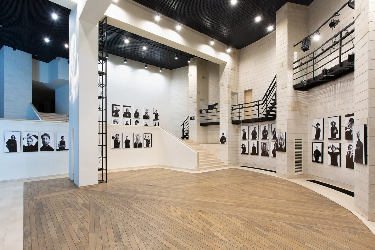 The exhibition space, with rows of portraits on its walls and a wooden floor.