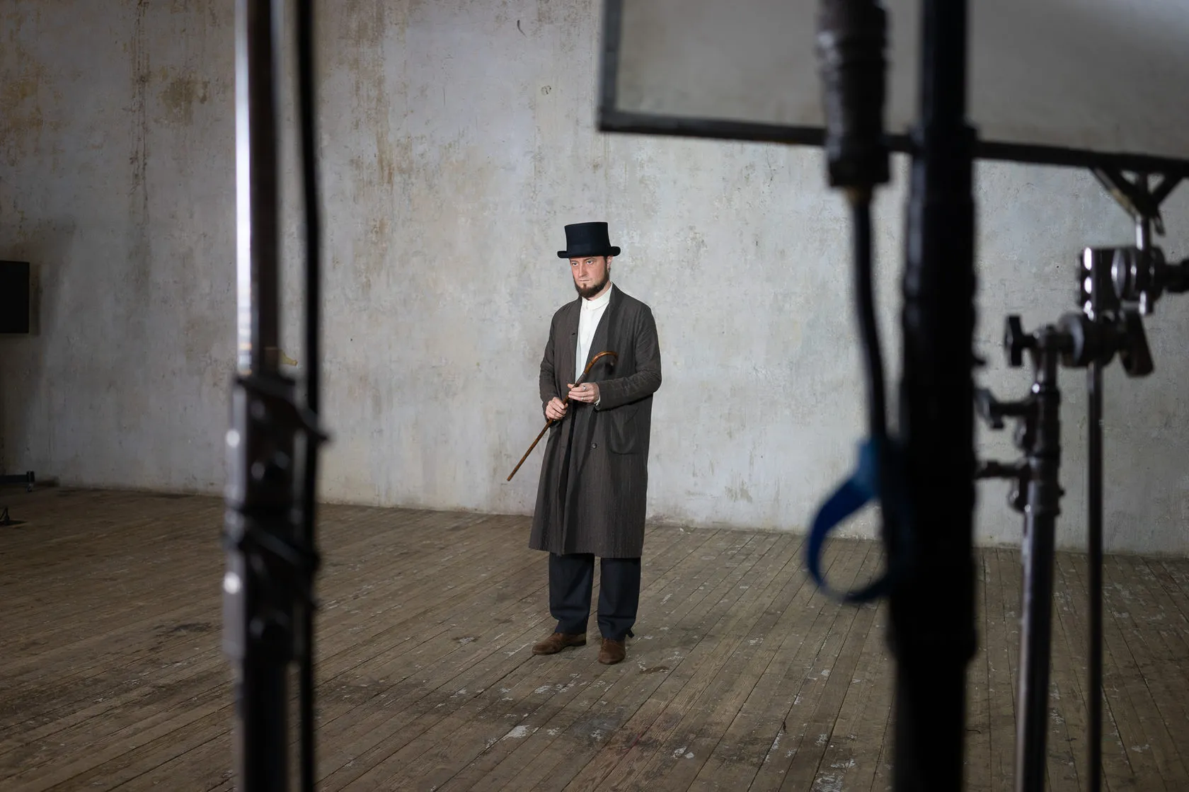 Behind the scenes: the actor in the top hat and long coat stands between light stands.