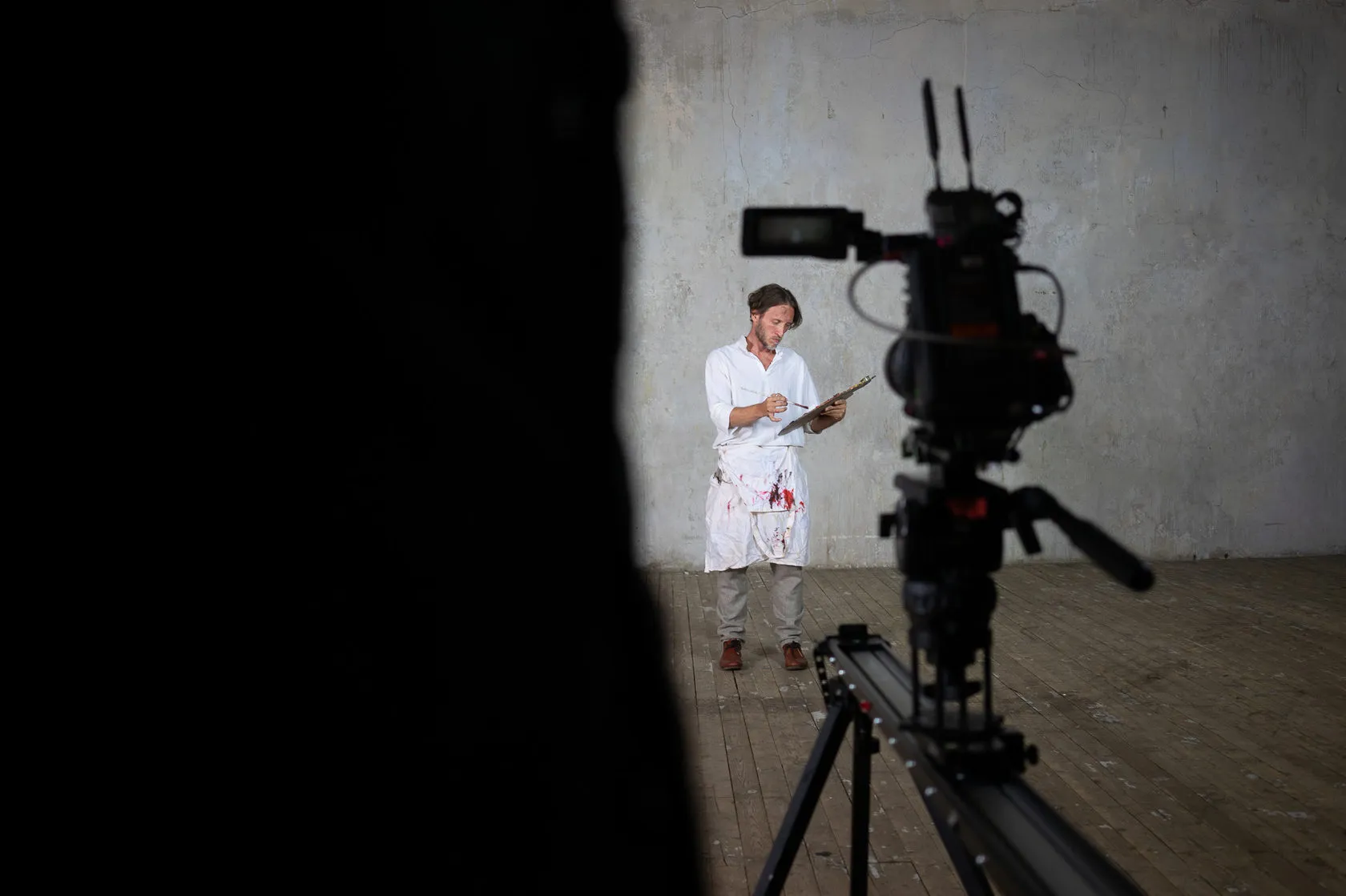 Behind the scenes: an actor in a blood-spattered white coat reads from a clipboard in front of the camera.