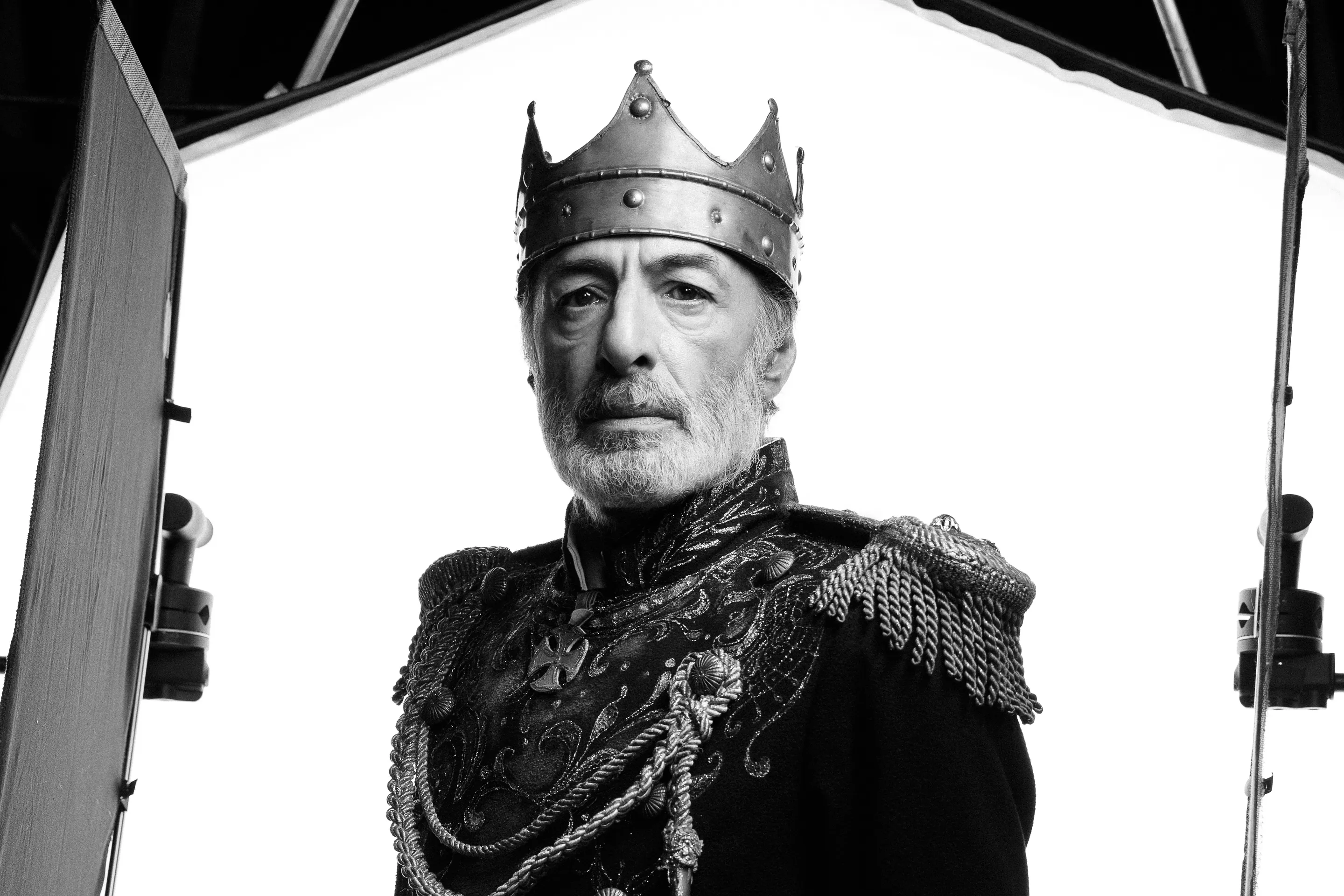 King Lear key visual by Andrei Kovalev: an actor in a crown and royal coat poses for a studio portrait, lighting rigs in frame.